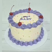 Cake with purple frosting, cherries, and '90's Baby' text on a white background