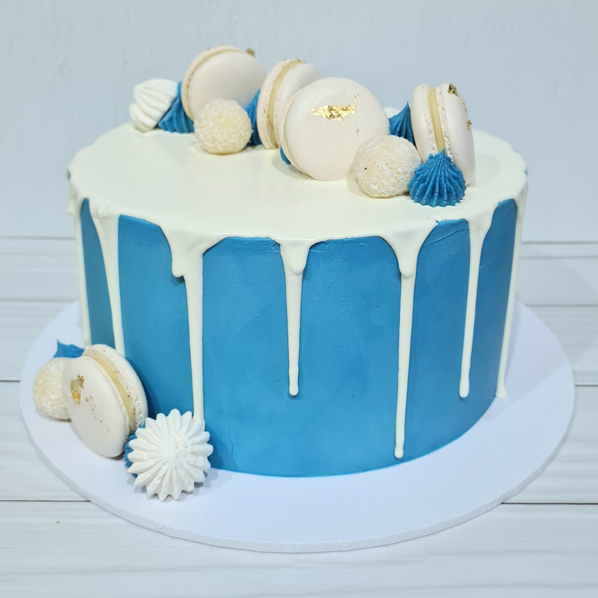 Blue cake with white frosting and decorative elements on a light gray background
