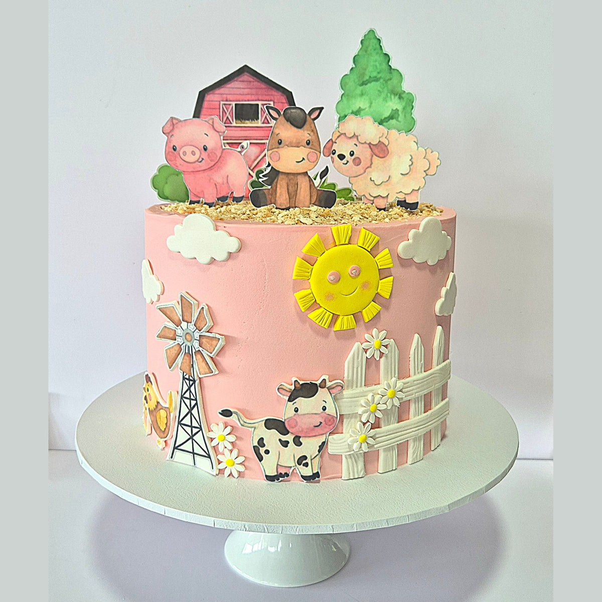 Children's birthday cake with farm-themed decorations on a white stand.