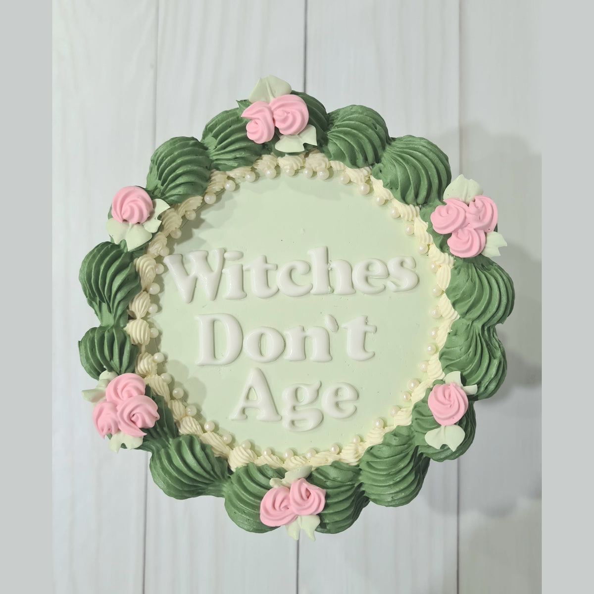Decorative wall art with 'Witches Don't Age' text and floral design on a light background