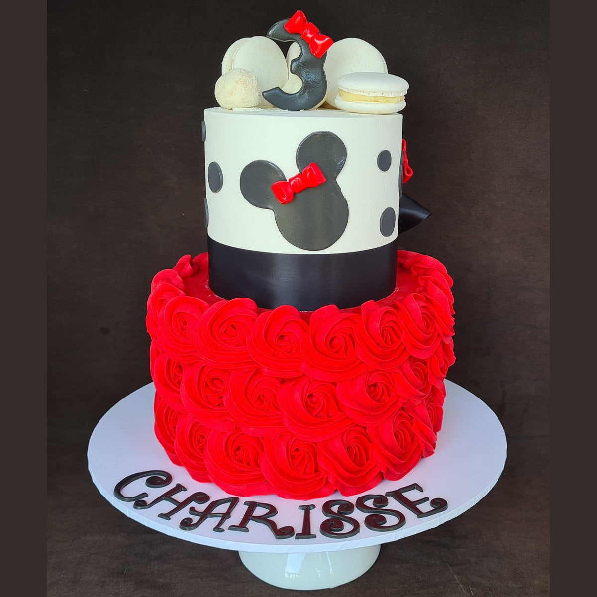 Two-tiered cake with red and black design, featuring the name 'CHARISSE' on a dark background.