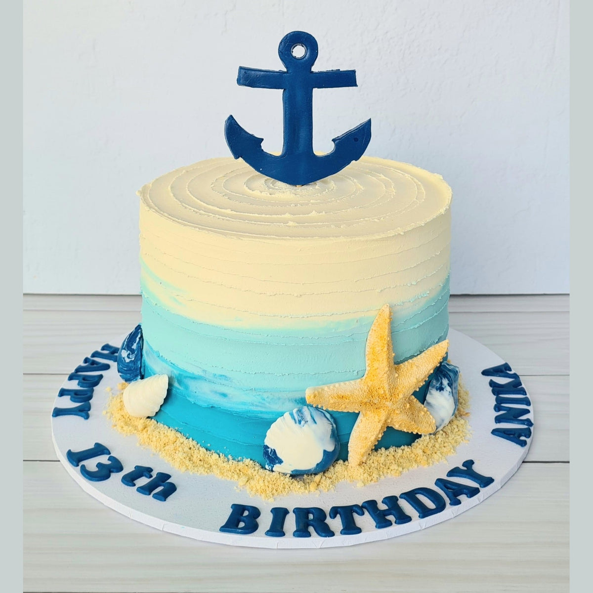 Nautical-themed birthday cake with an anchor on a white background