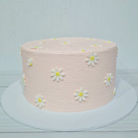 Pink cake with white daisy flowers on a light gray background