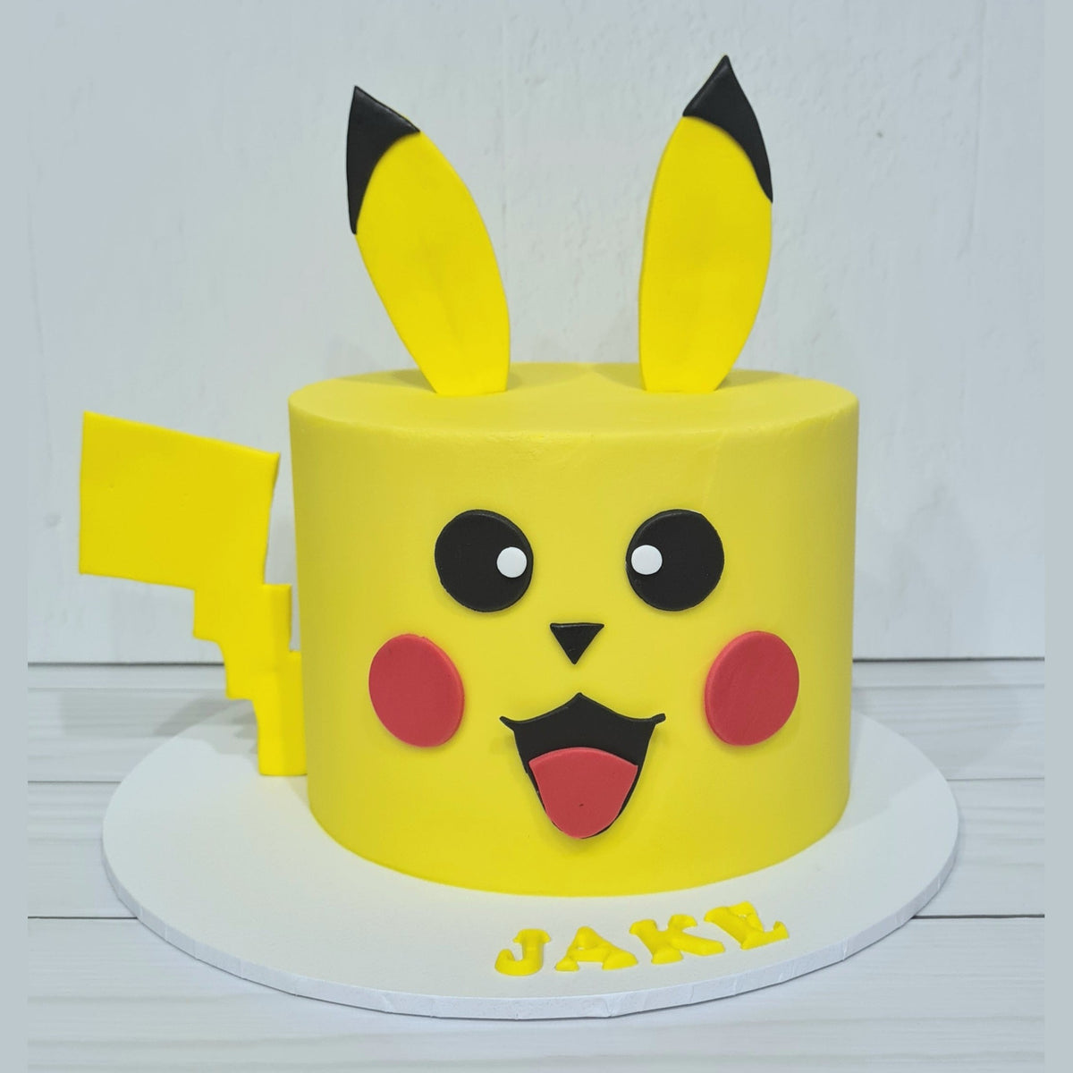 Yellow cake shaped like Pikachu with black and red details on a white background