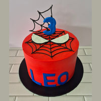 Red cake with spider web design and number 3 on a white background