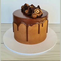 Chocolate cake with chocolate decorations on a white stand against a light background