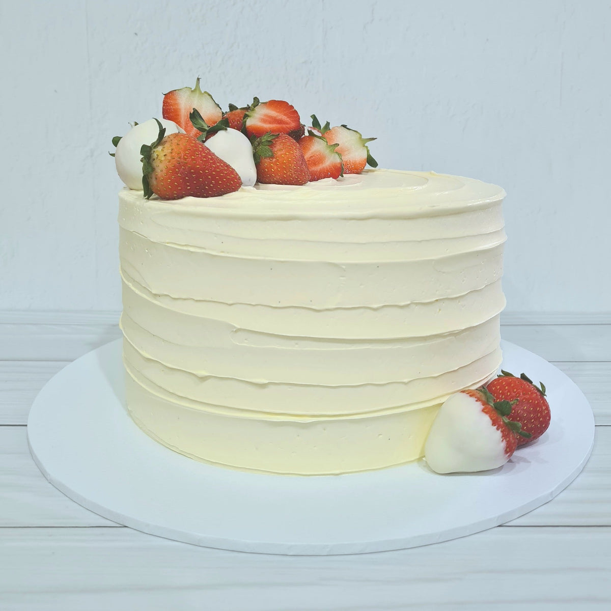 White frosted cake with strawberries on a white background