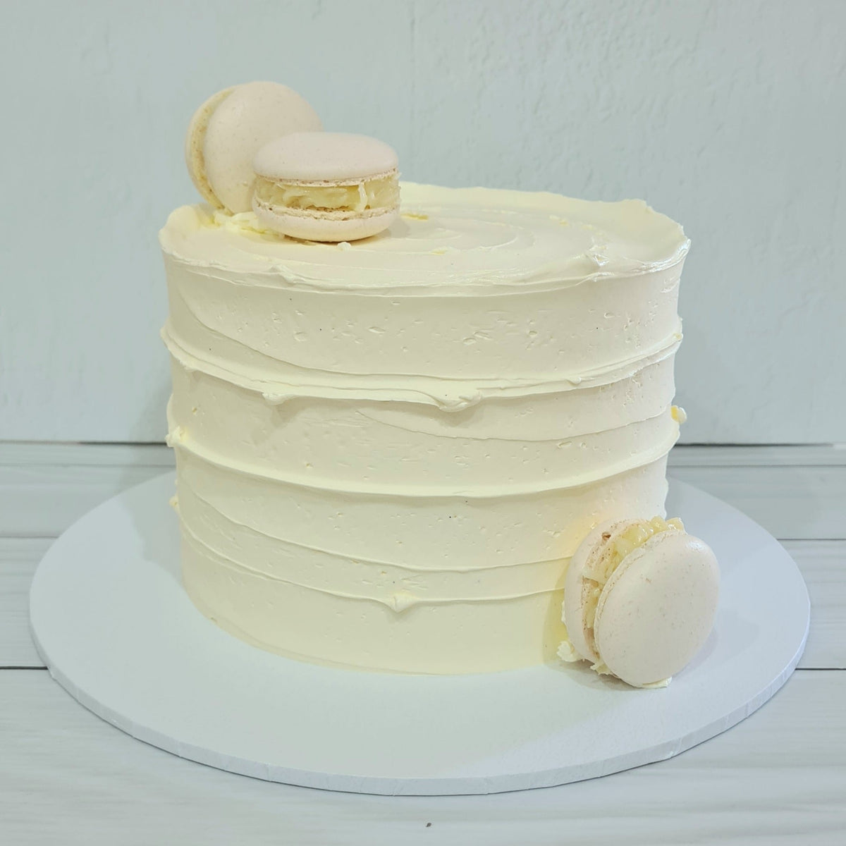 White frosted cake with macarons on a white background